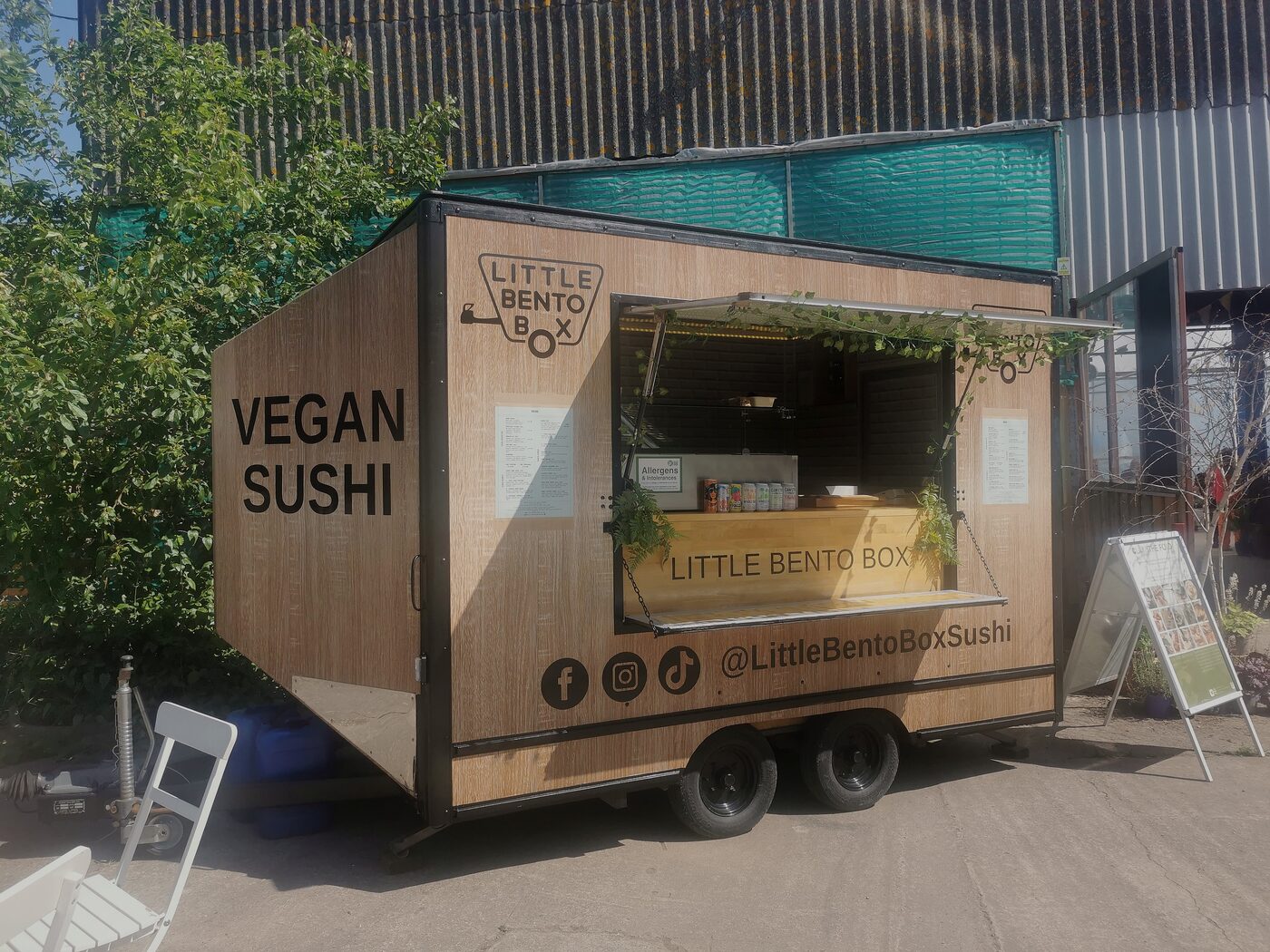 Inari, the wood-clad Little Bento Box sushi trailer, set up at an event with the serving hatch open and Vegan Sushi lettering on the side.